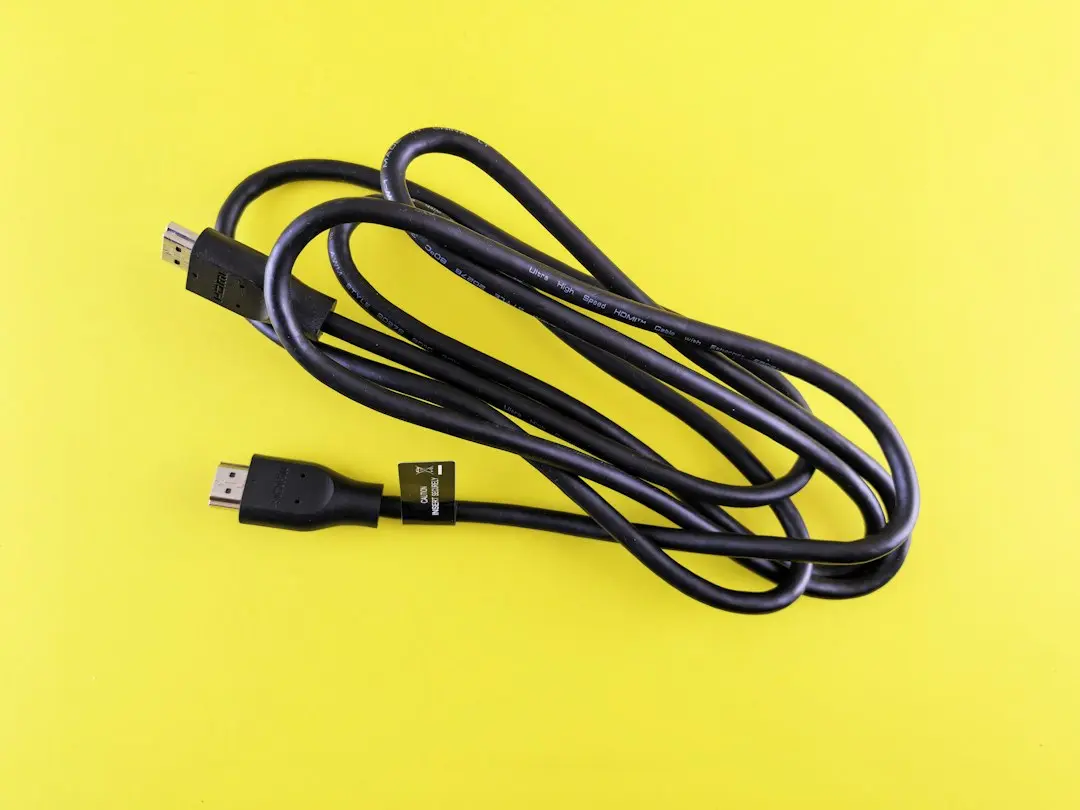A coiled black HDMI cable on a yellow background, the plug a streaming stick or console uses to bring the Nufu TV app to a TV